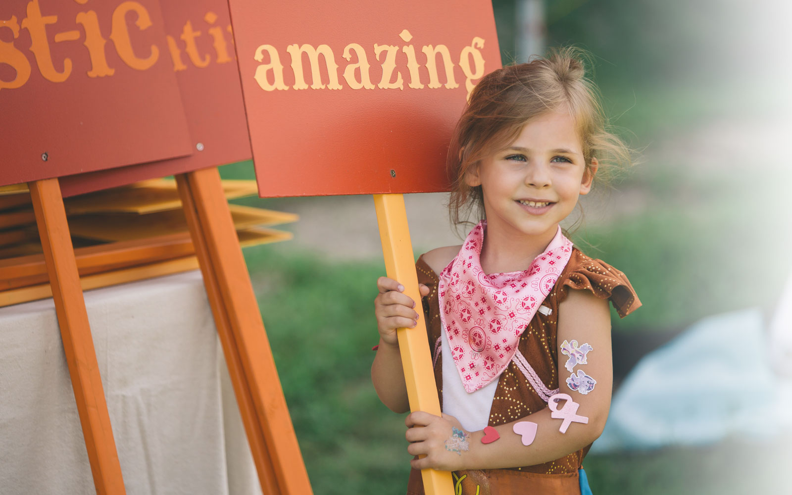 A young girl holding a sign that reads "amazing."