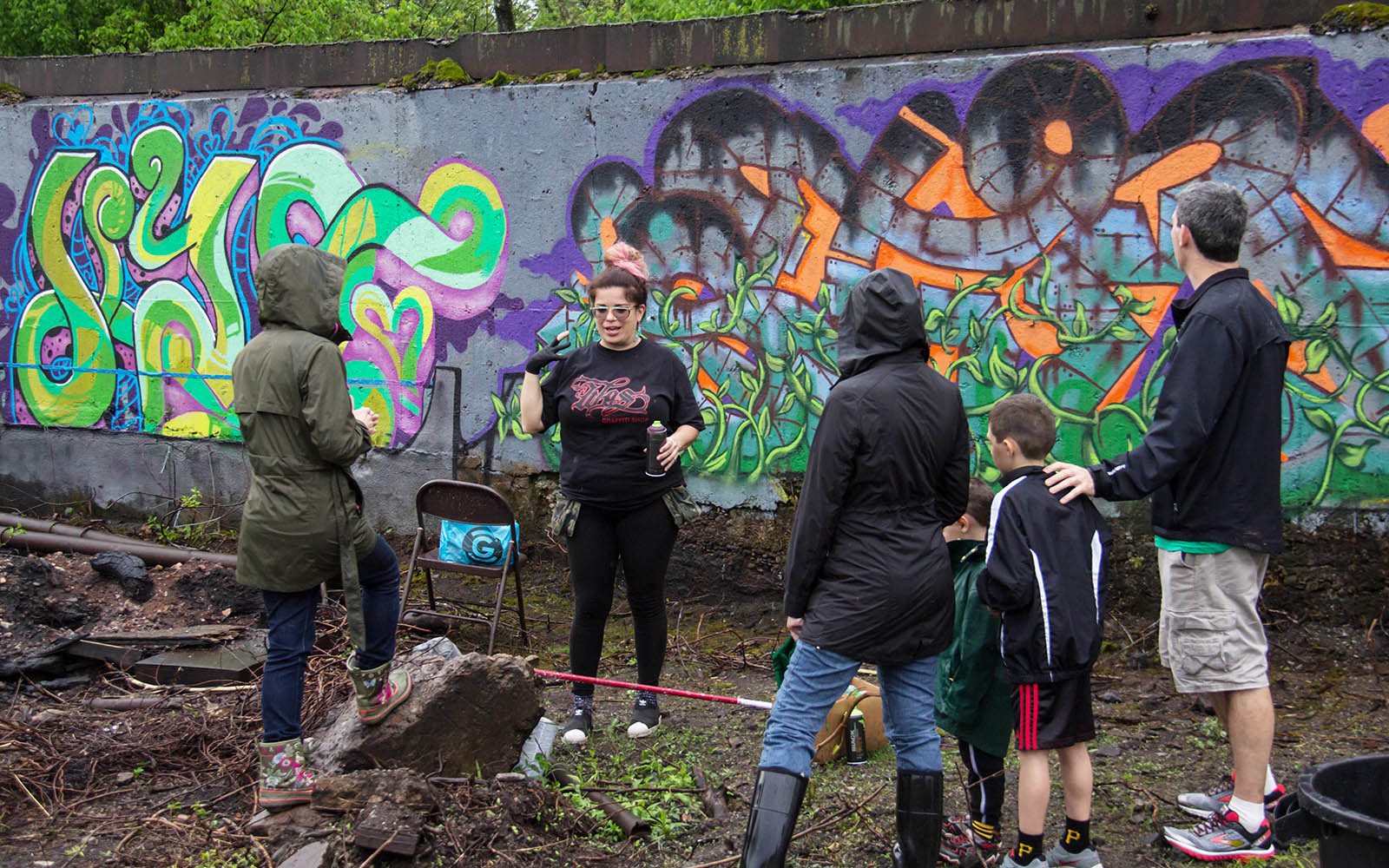 Graffiti artist Stef Skillz speaks with a family with a her mural in the background.