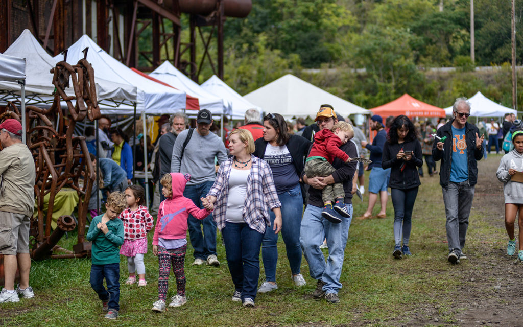 Family walk through a crowd with activity tents behind them.