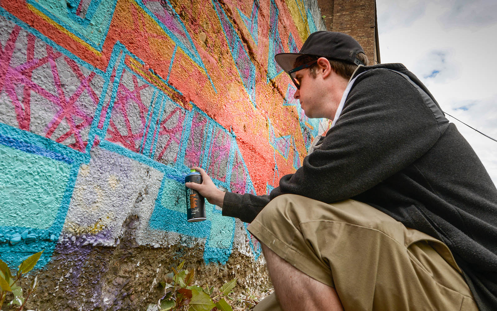 A man spray paints on a wall.