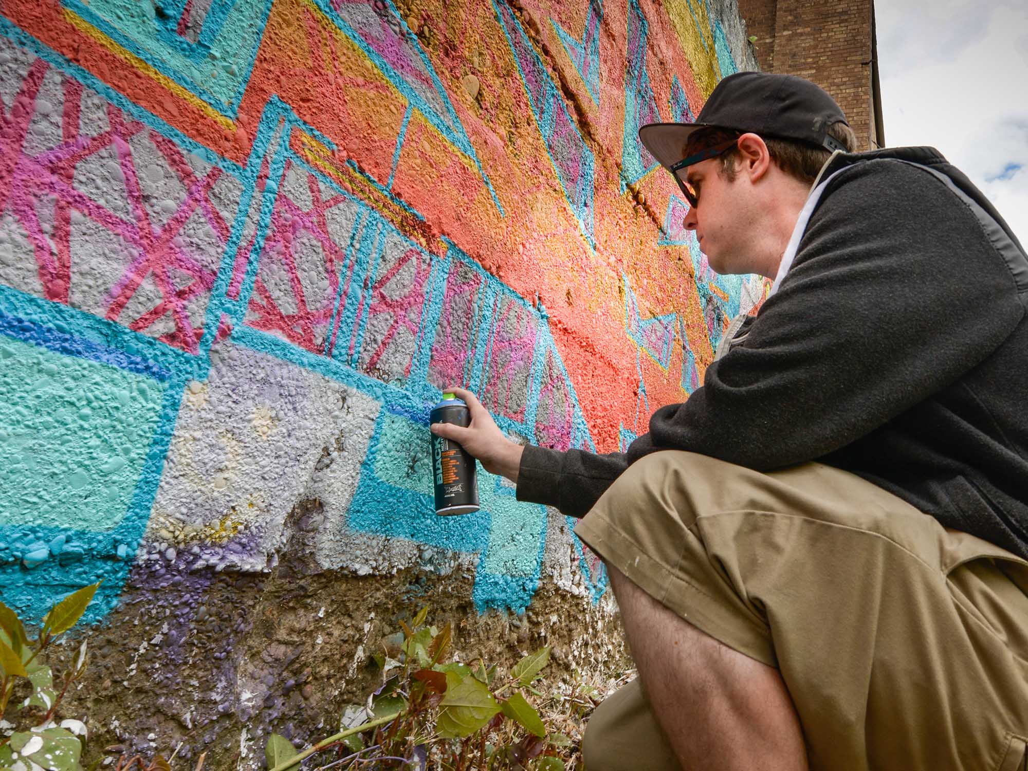 A man spray paints on a wall.