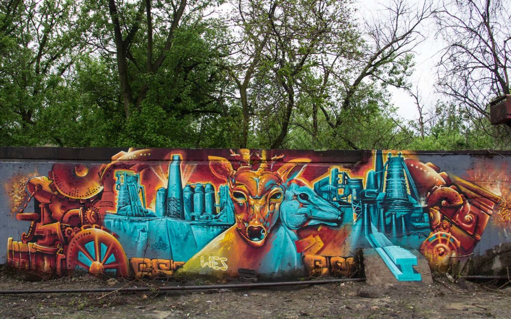 A man photographs a graffiti wall.