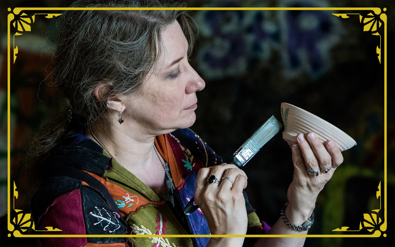 woman carefully paints glaze on a pot to be fired during festival of combustion