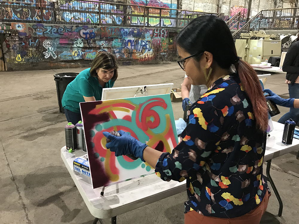 workshop participant creates her aerosol painting