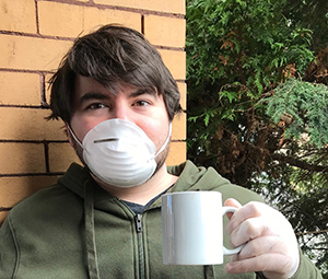 portrait of the artist, a young man wearing a mask and glove with a coffee mug