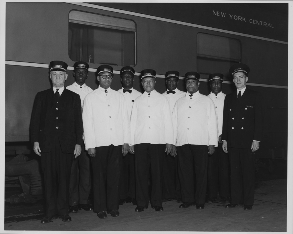 7 Pullman Porters (black men) stand with a steward and a conductor (white men).