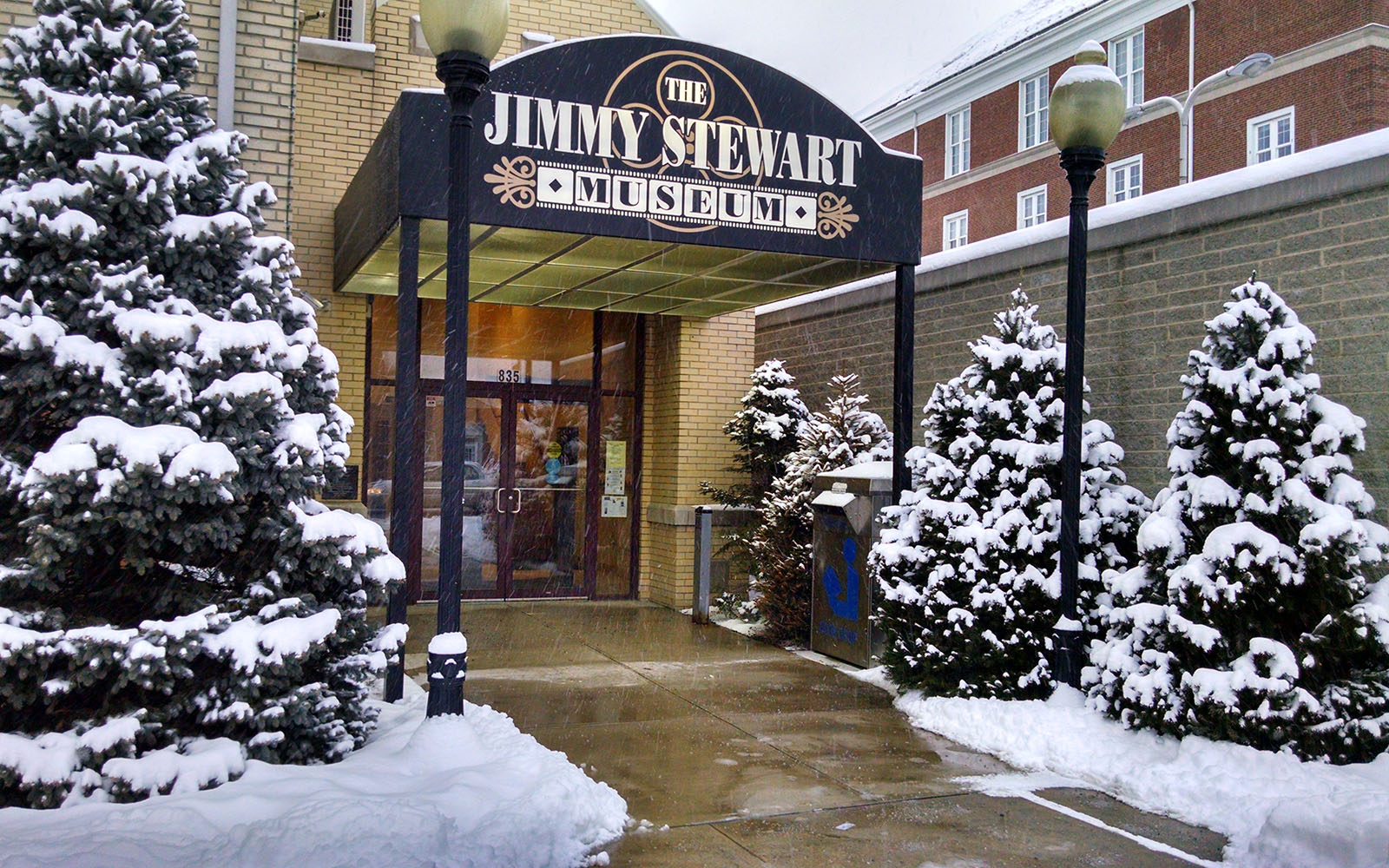entrance to museum flanked by snowy Christmas trees