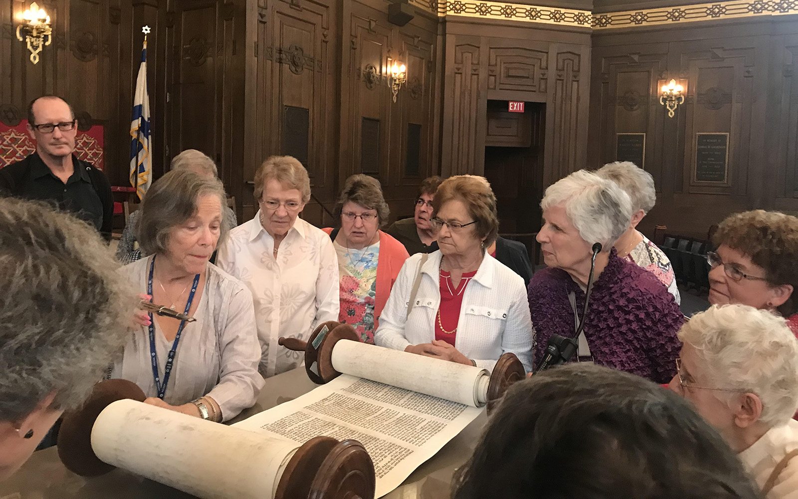 A group gathers around an ancient Torah at Rodef Shalom Temple
