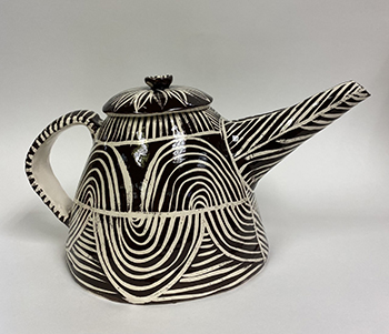 A black teapot with white concentric half moon circles that create a geometric pattern.