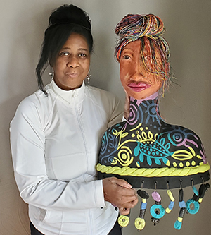 A black woman in a white shirt holds a colorful ceramic bust that appears as if it could be a self-portrait.