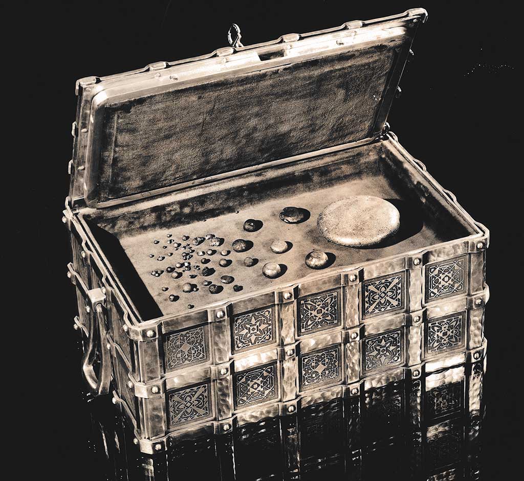 A black and white photo of aluminum stones in an ornate aluminum box. 