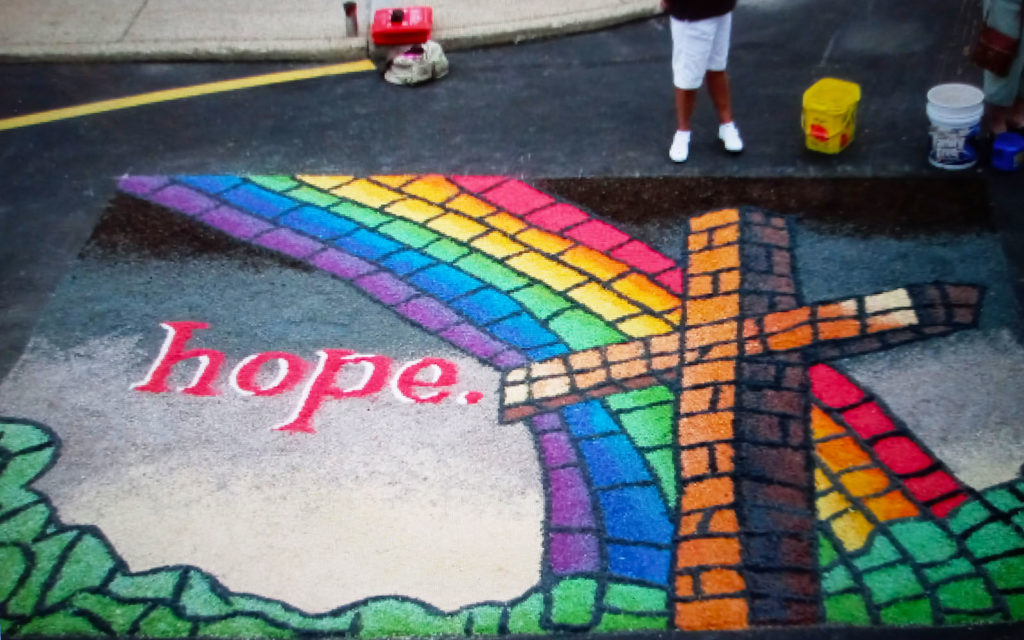 a sawdust carpet with a rainbow and a cross