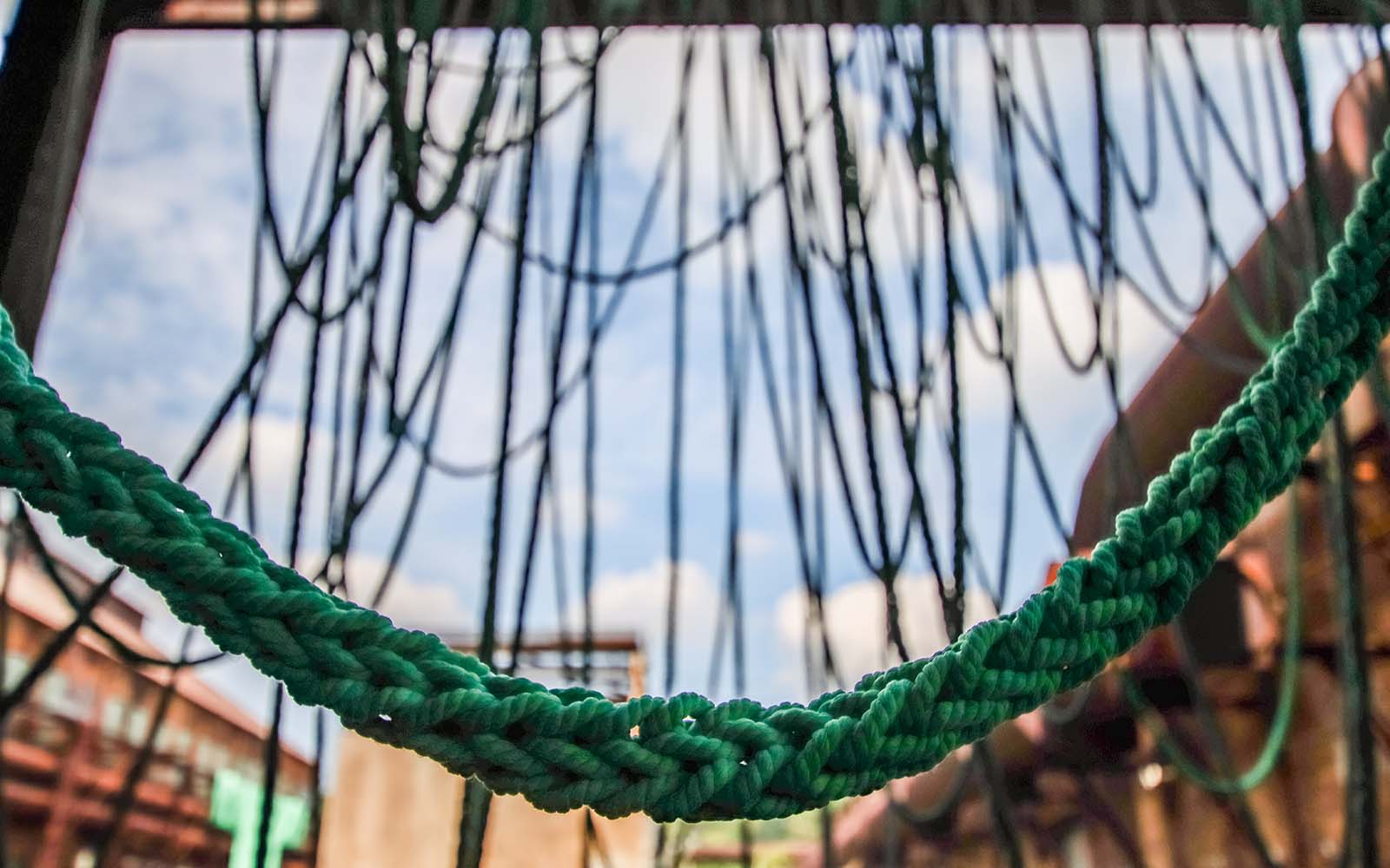 Knitted green cords hanging from the cast house wall.