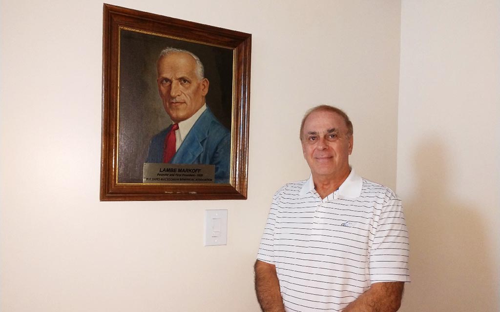 A man stands in front of a portrait.