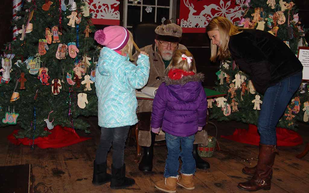 Two young girls and their mom talk to Santa.