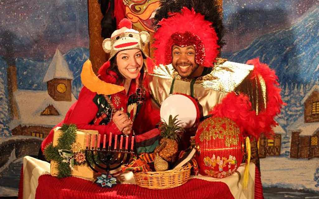 Two actors in holiday costumes mug for the camera. 
