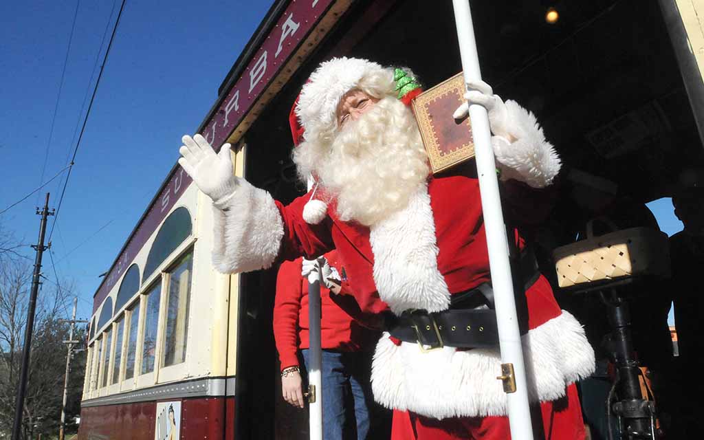 A Santa waves from a Trolley.