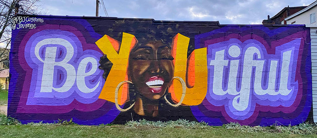 A black woman's face represents the letter "U" in a mural that spells out Be-You-tiful