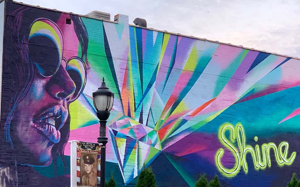 A colorful mural of a woman's face next to a diamond and the word "Shine"