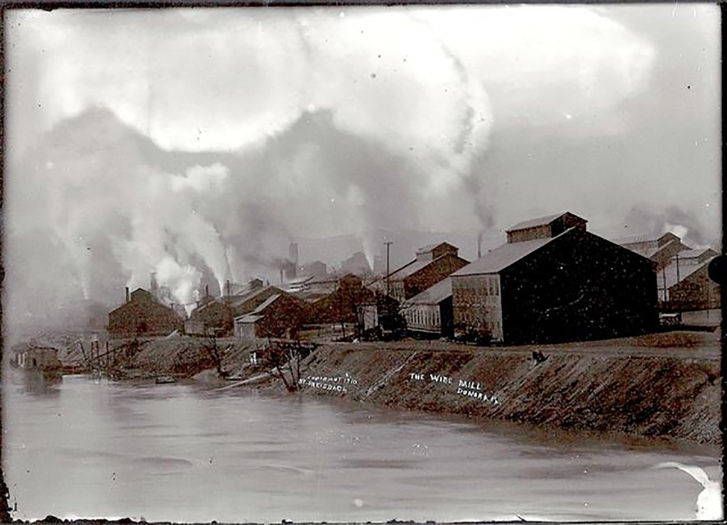 Smoke bellows from at least ten industrial buildings along a river in this historic image.