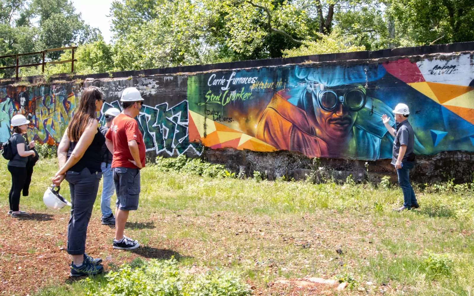 People look at a graffiti mural while someone points at it.