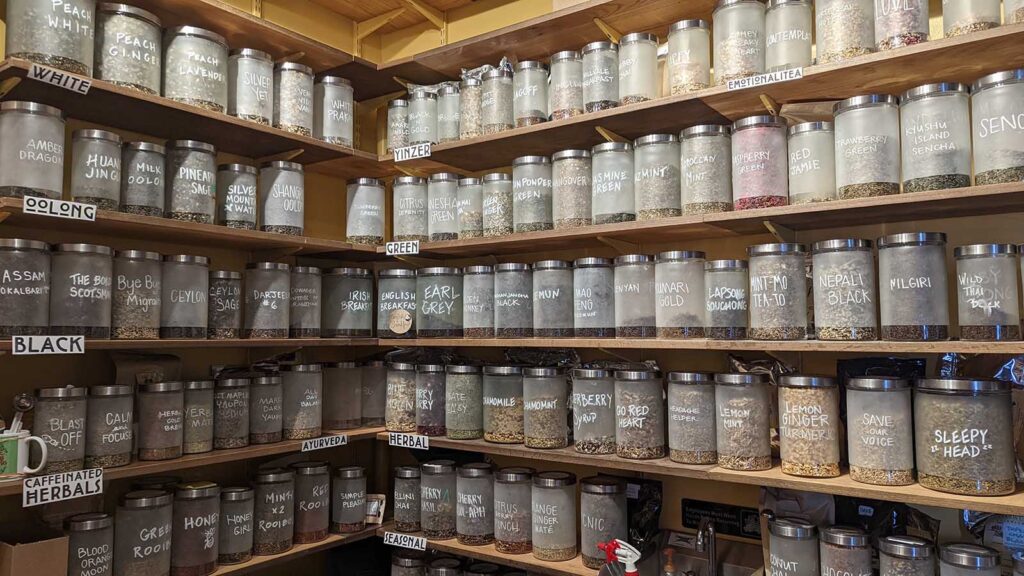 Five shelves lined with about 100 jars of different teas.