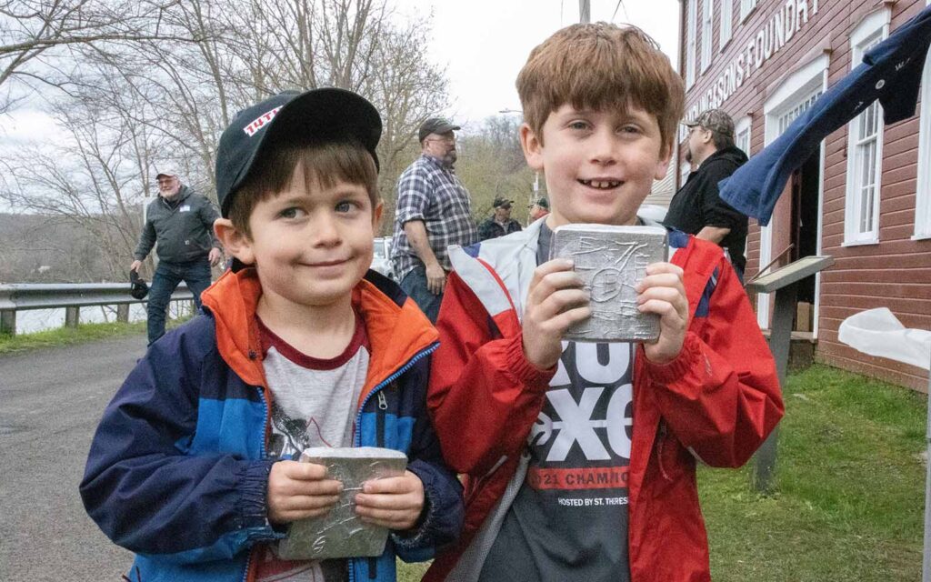 Two young boys show off their scratch mold aluminum cast tiles.