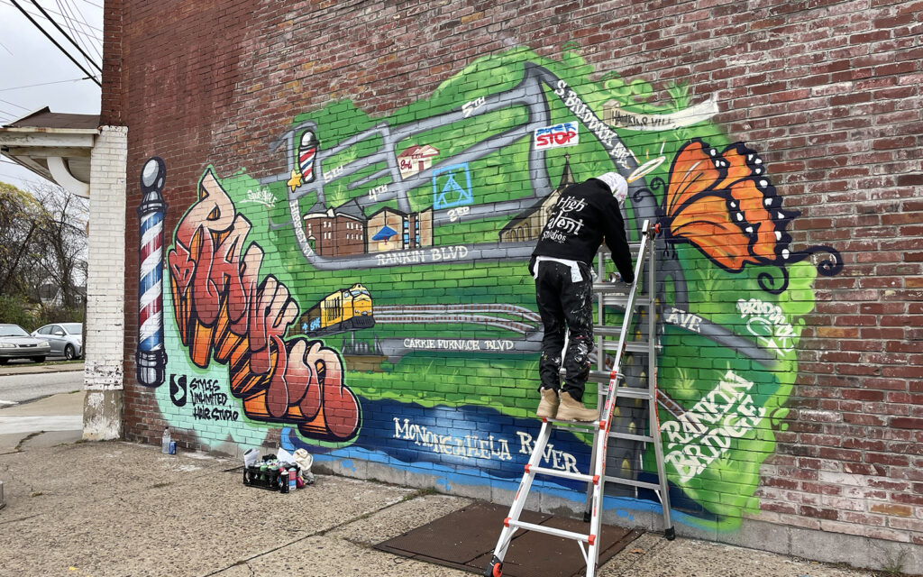 Artist Latika Sewell works on her mural for Rankin Borough as part of industrial grit and graffiti