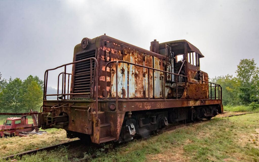 The train engine with layers of paint visible amongst the rust. 