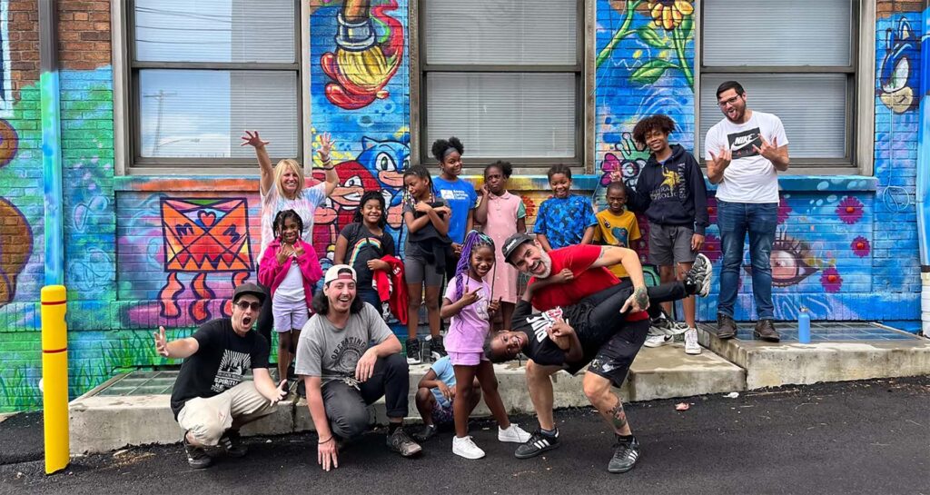 Students pose with rivers of Steel artists in front of a new mural created with the Rankin Christian Center in Raknin, Pennsylvania