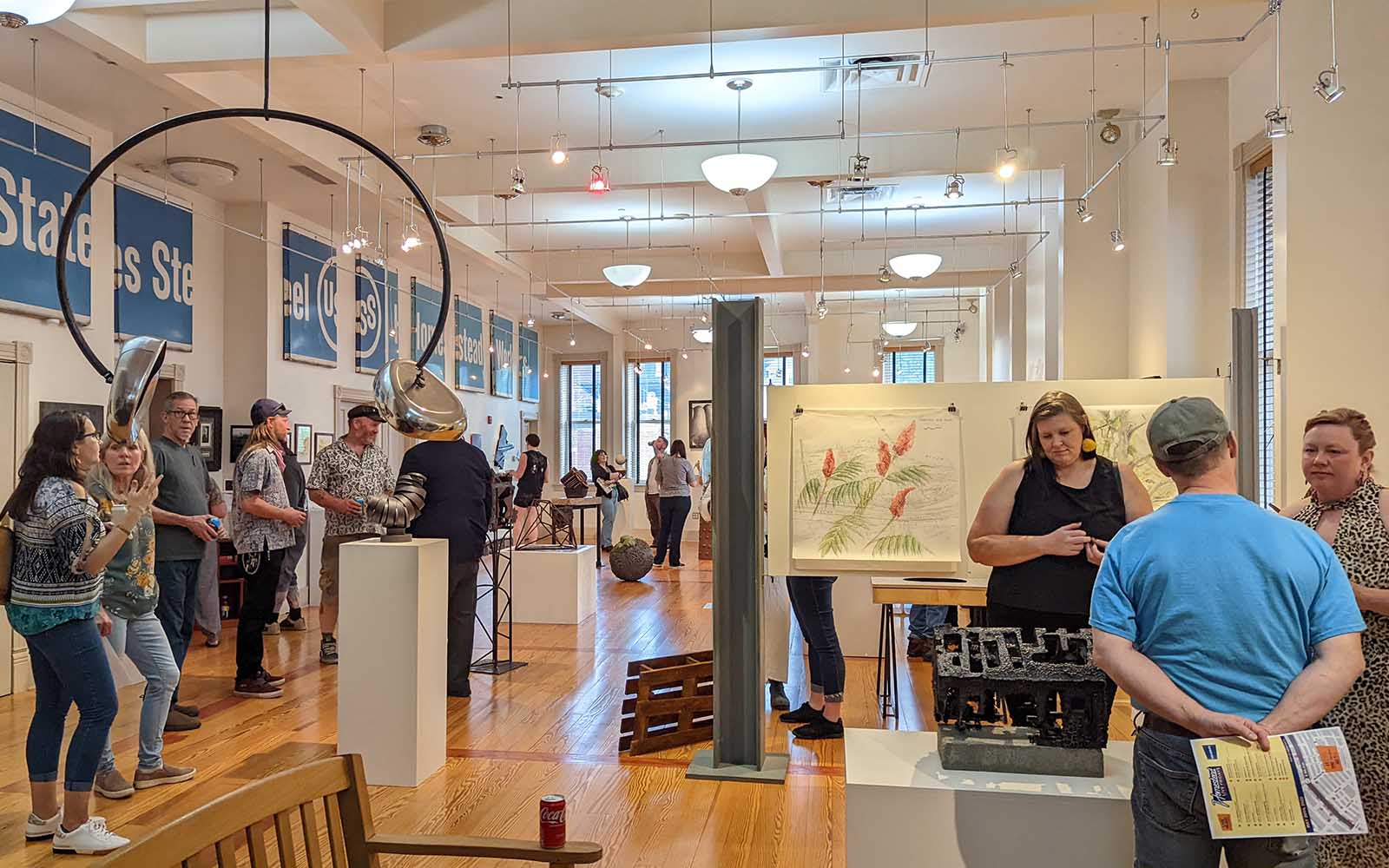 People talk in small groups at an exhibition opening.