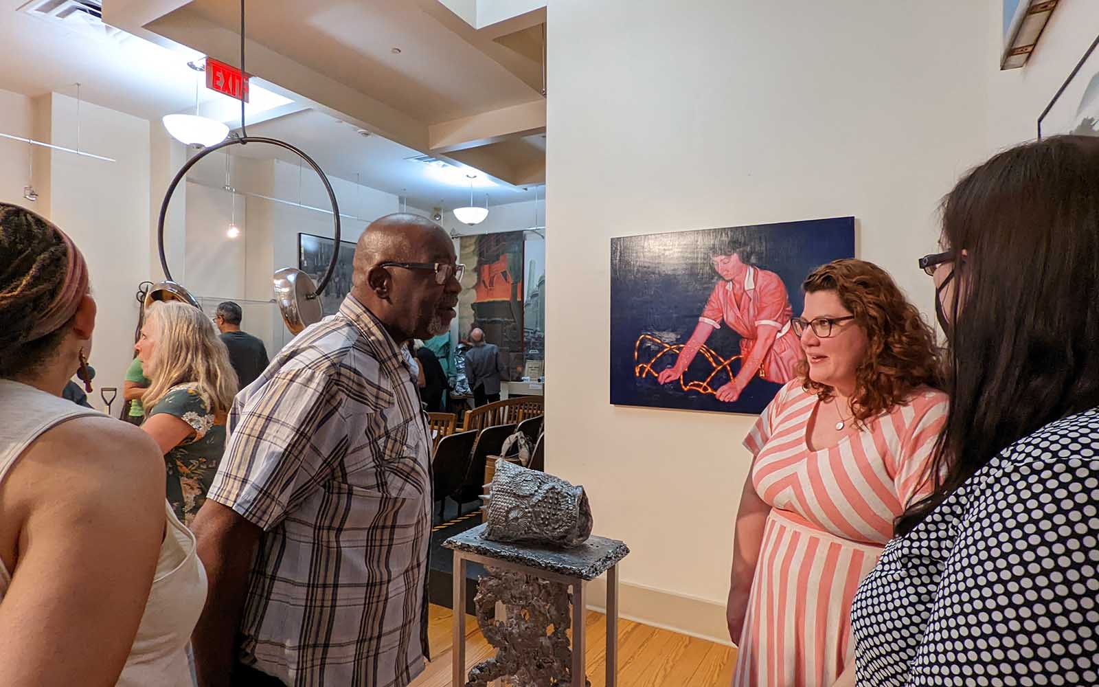 People talk in small groups at an exhibition opening.