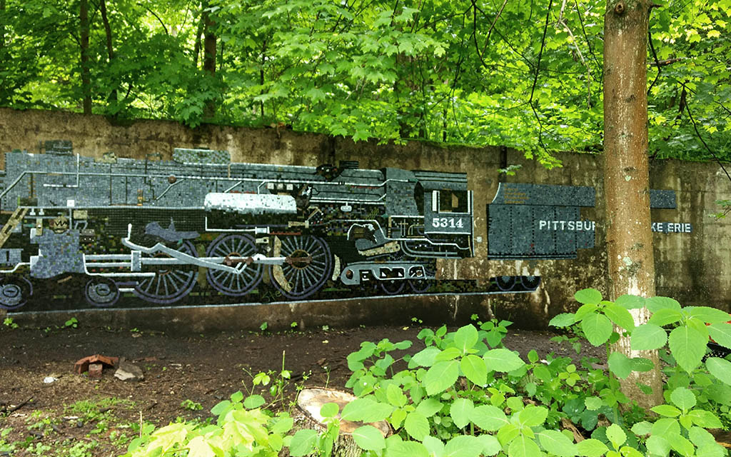 A nearly lifesize mosaic train adorns a concrete wall. 