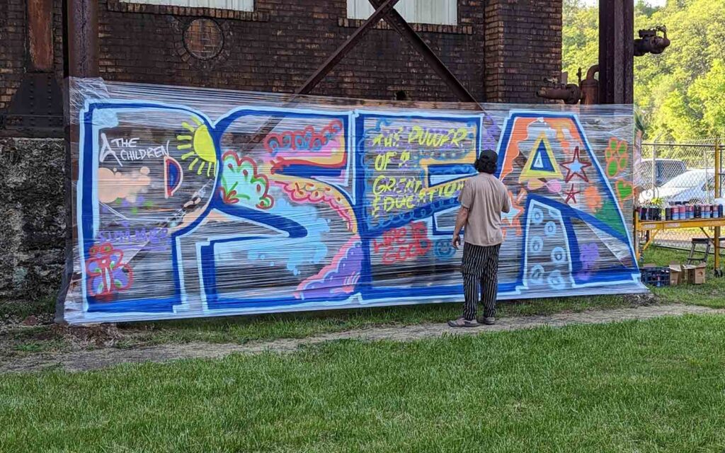 A man add to a "PSEA" graffiti mural.