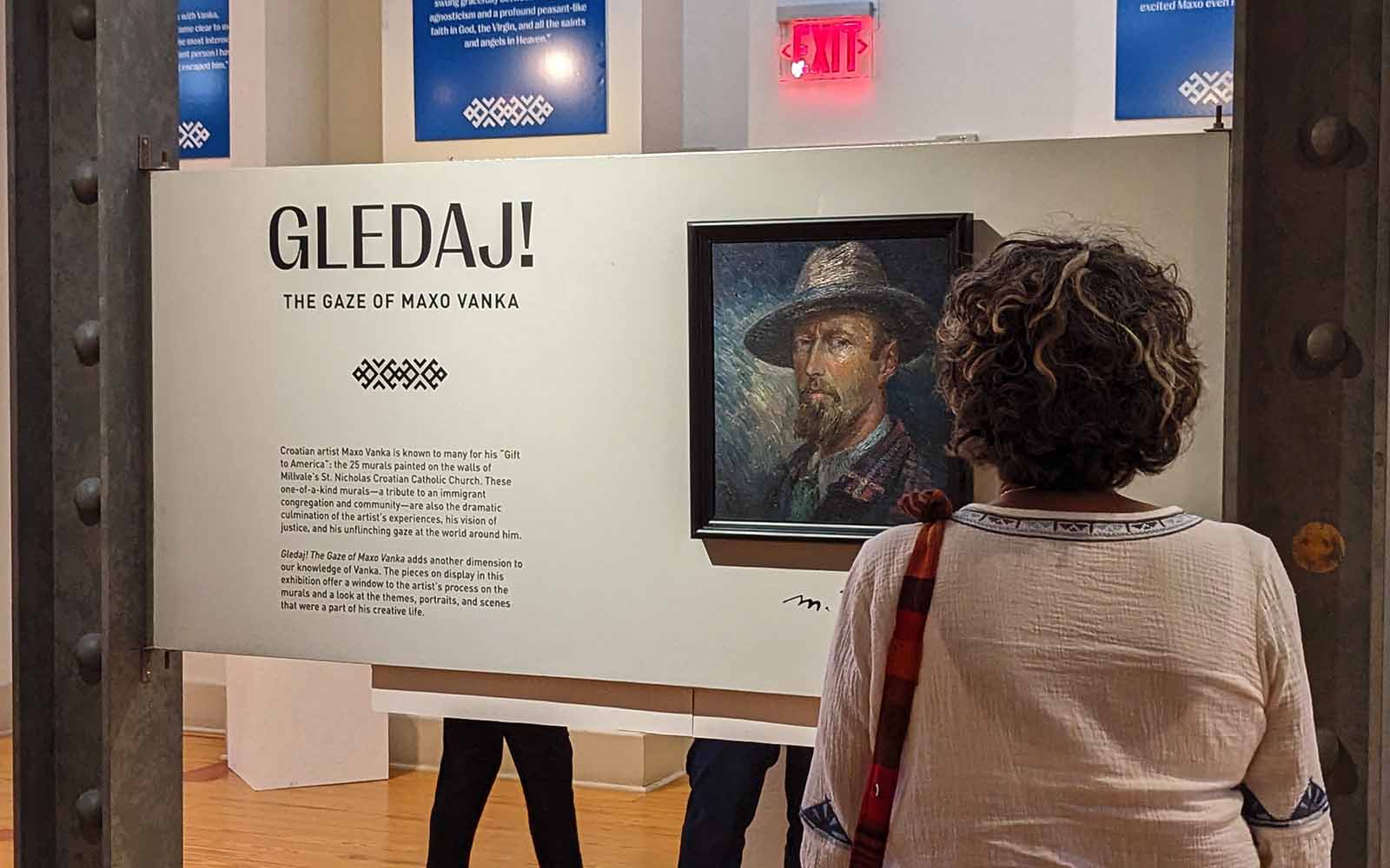 A woman looks at the signature image for the Gledaj exhbition, a self portrait by Maxo Vanka.