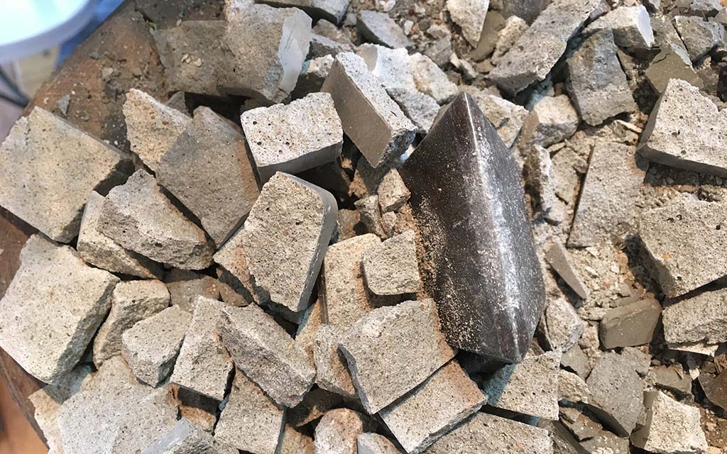 Small gray gravel like concrete tesserae surrounding a hardie chisel. 