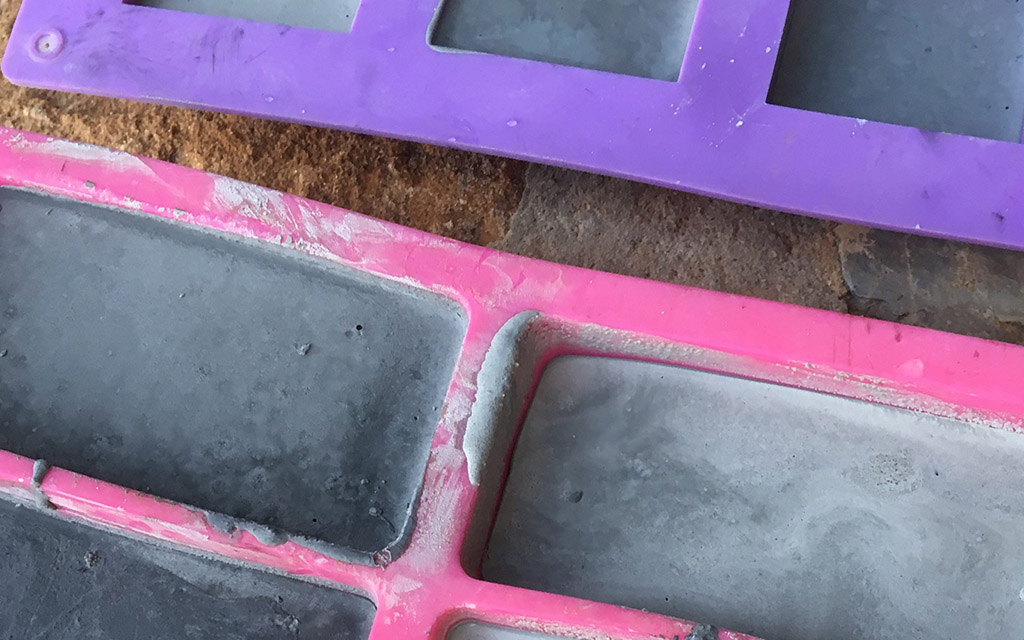 Different shade of gray concrete fill up ice cube molds.