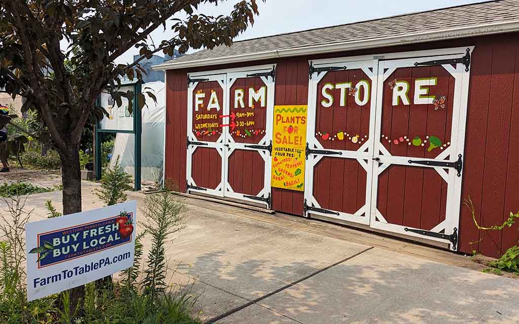 A red and white structure is labeled "Farm Store" on it's barn-like doors. A nearby sign reads "Buy Fresh, Buy Local" and "FarmToTablePA.com"