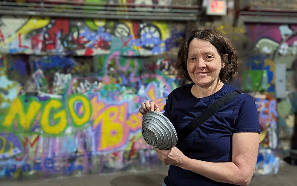 A woman hold up her doodle bowl with a spiral design.