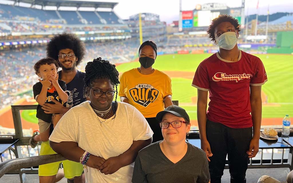 A group of teens, adults and a child pose for a photo during a ballgame at PNC park.