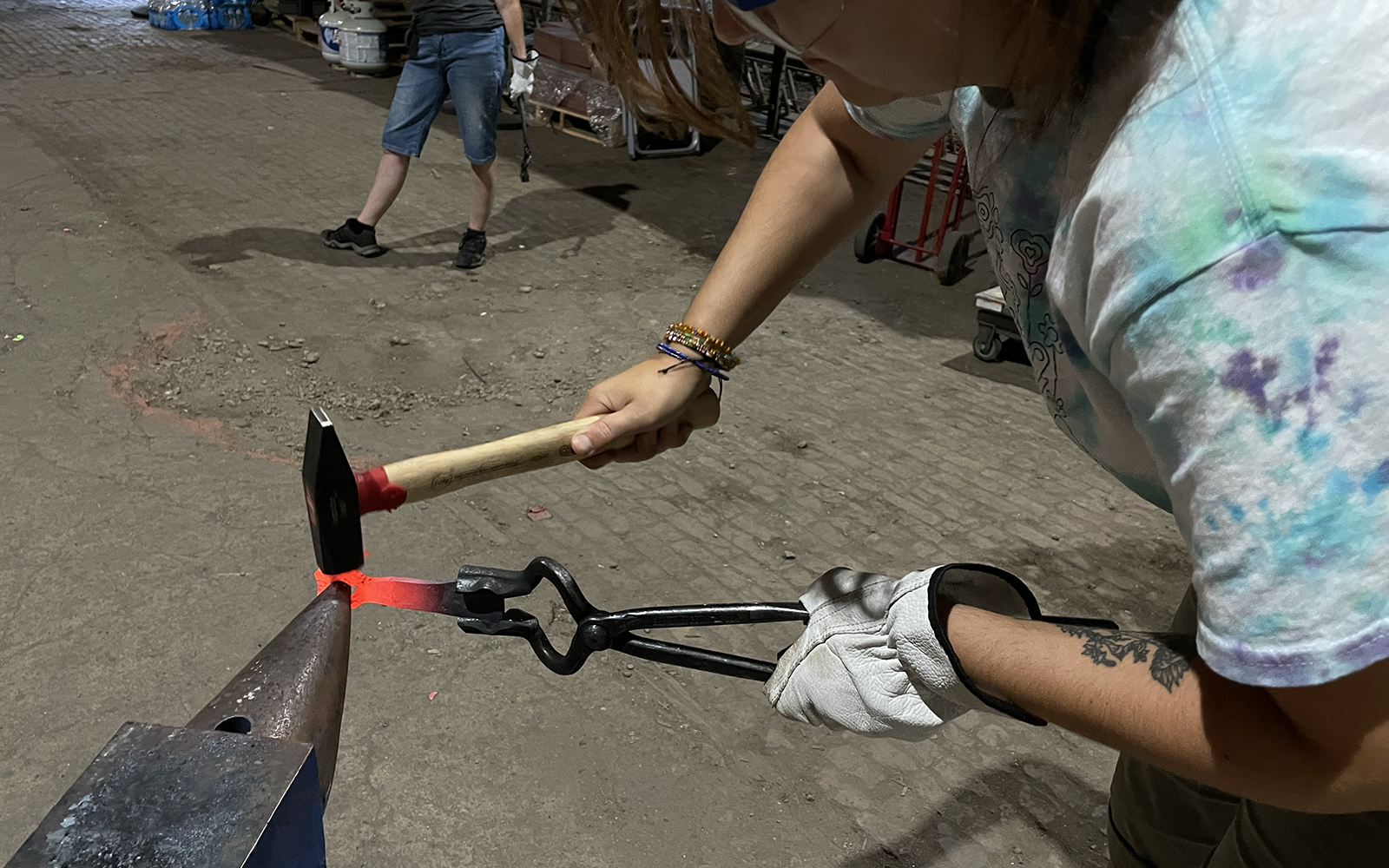 workshop participant hammers her forged bottle opener to drift the open end further.