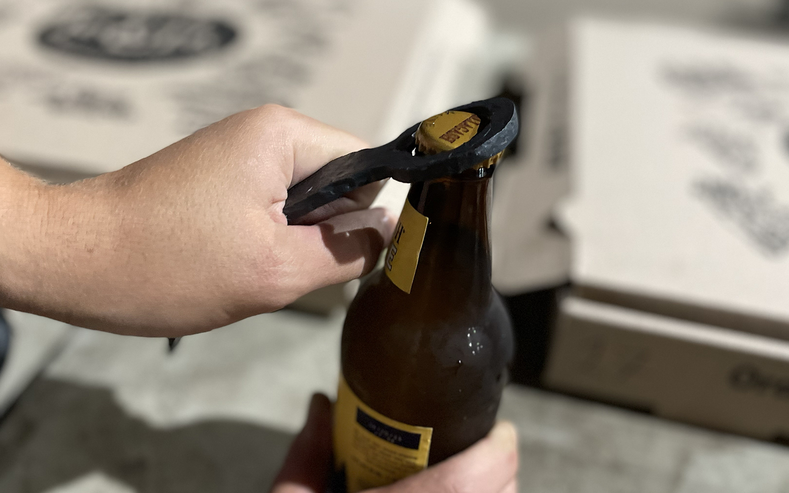Workshop participant uses their completed bottle opener to pop the top on a cold refreshing bottled drink