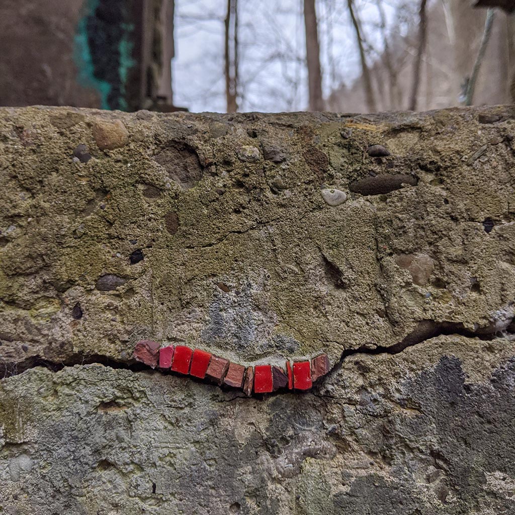 Ten red stones are placed in a line following a crack in the cement wall. 