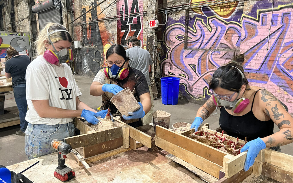 workshop participants work collaboratively to prepare their patterns for sand molding