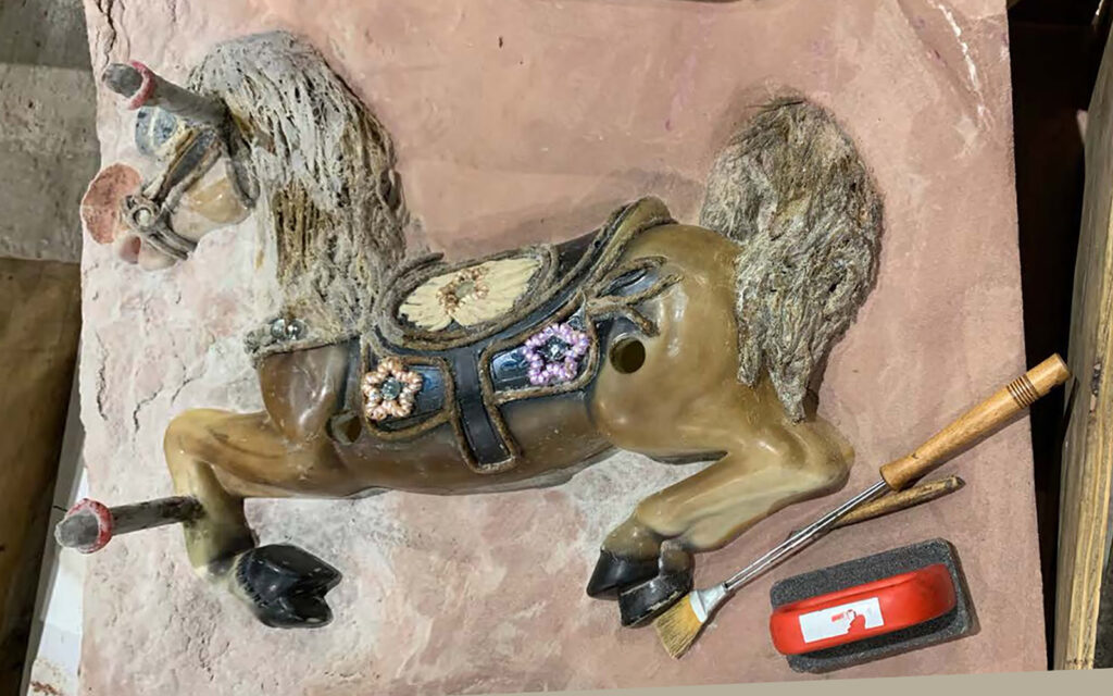 workshop participant and artist, Marsha Pells prepares one side of her sand mold for a rocking horse.