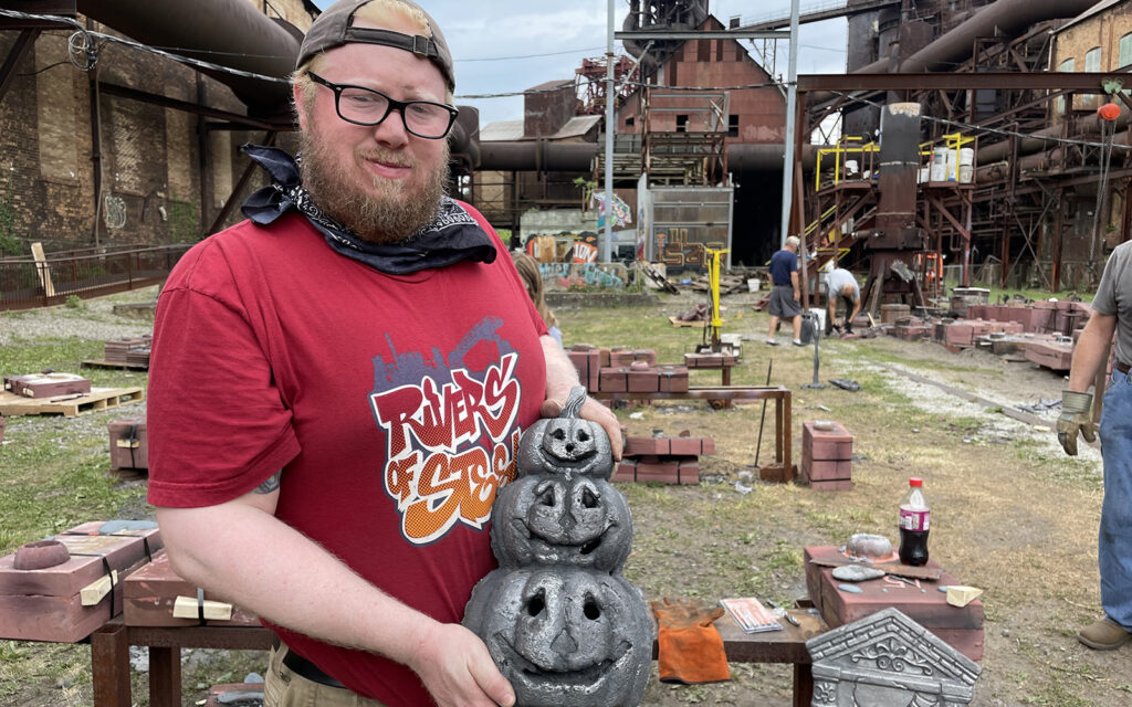 workshop participant holds up his pumpkins successfully cast in iron.
