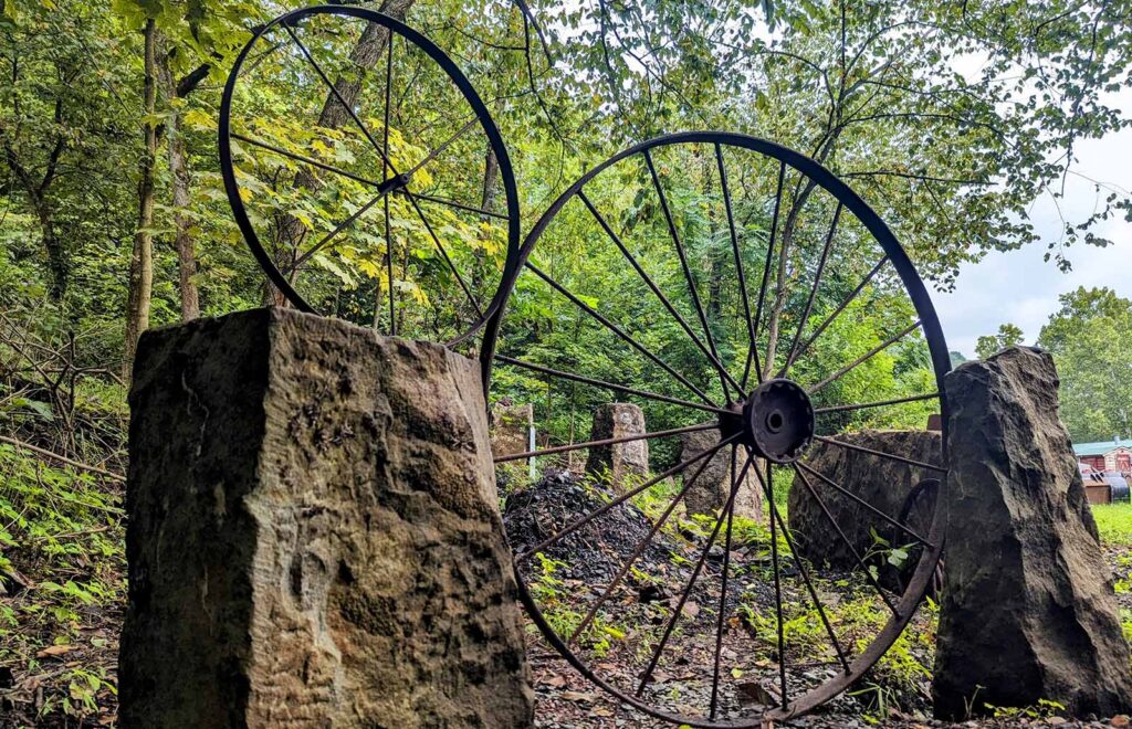 Two large metal "wagon" wheels are perched between large bridge stones.