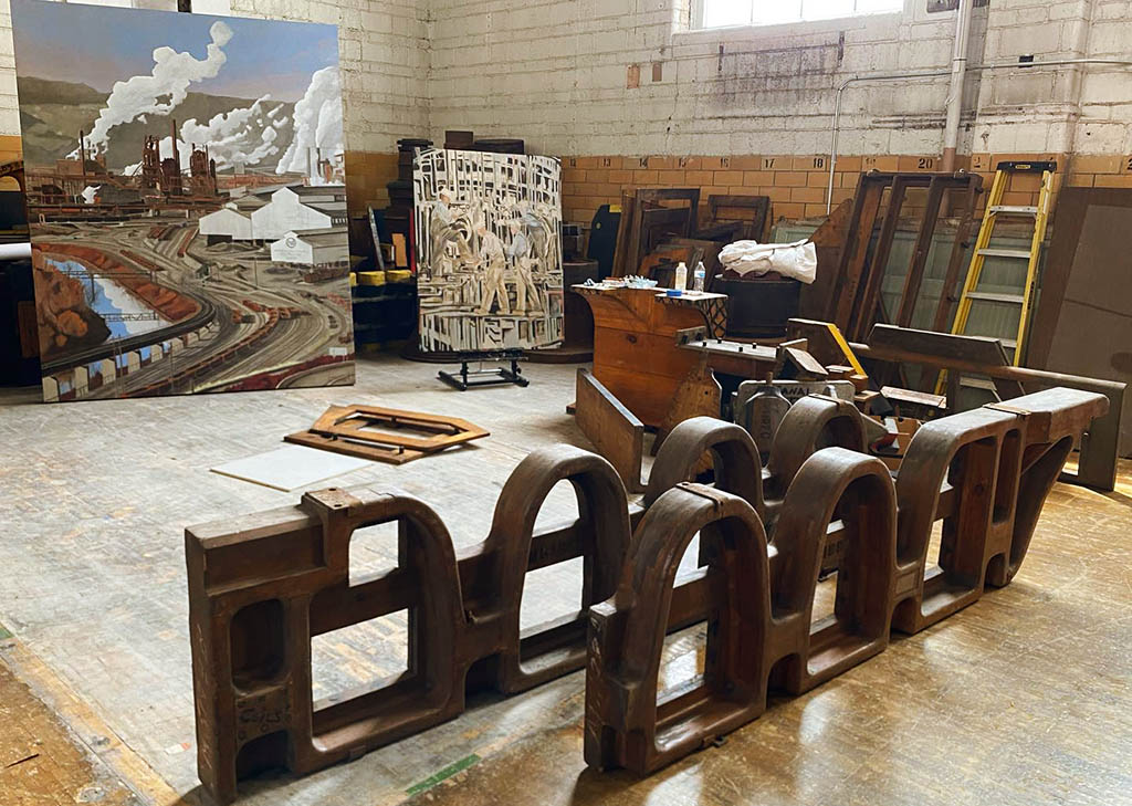 Two uniquely shaped molds sit in the studio space with art and other patterns lined near the walls around them.