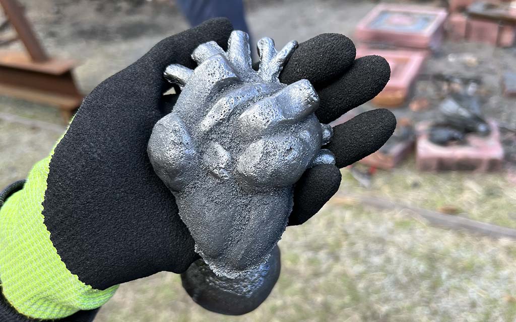 A gloved hand holds an iron heart.