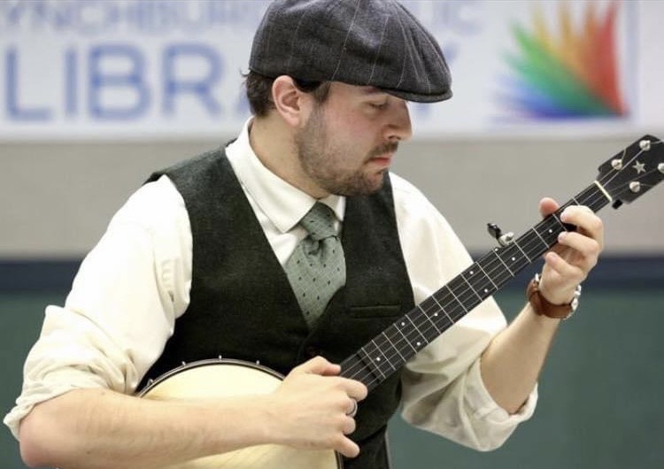 A banjo player wearing a vest and cap.